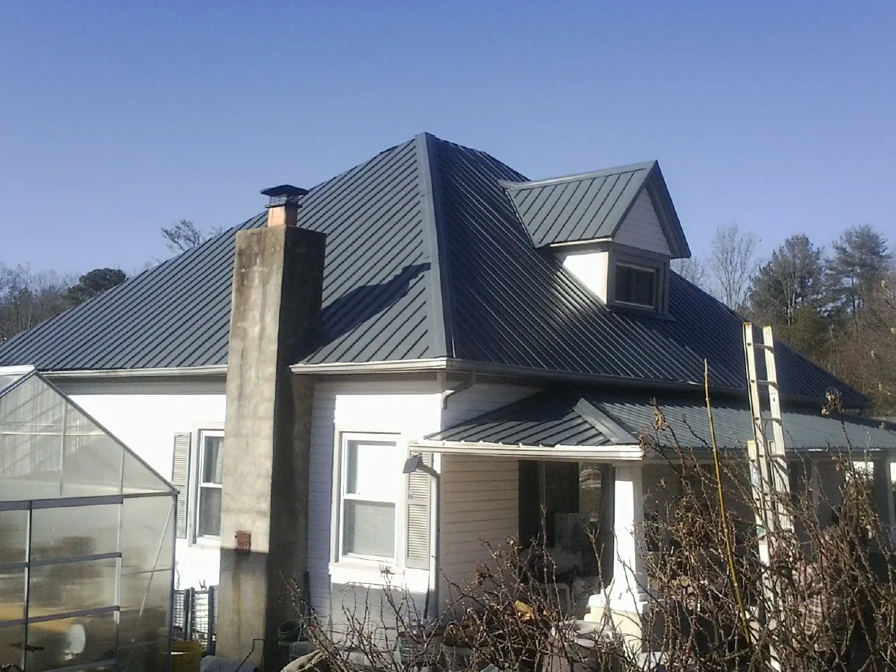 Dark blue standing seam metal roof on a white farmhouse with dormer — Slate & Tile Roof Repair by Roofing Brothers in Clarkia