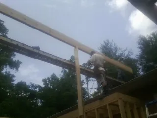 Carpenter setting a ridge beam over a new addition frame — Ice Dam Removal by Roofing Brothers in Clarkia