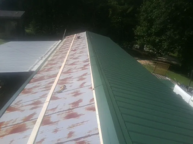 Old rusted panels beside newly installed green metal roofing — Wind Damage Roof Repair by Roofing Brothers in Clarkia