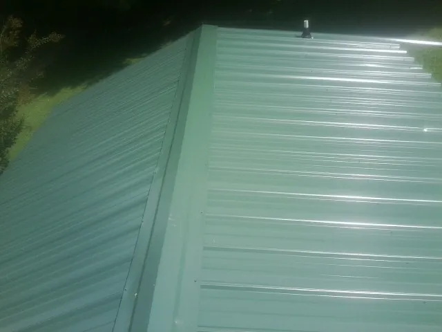 New green metal panels meeting at the ridge of a roof — Flat Roof Repair work by our crew in Clarkia