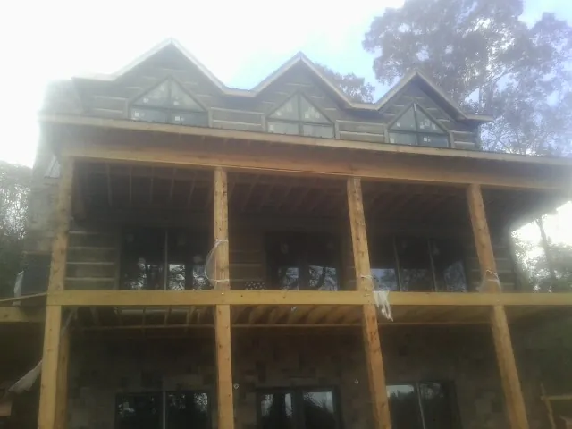 Dormers and porch framing on a large log home under construction — Roof Coating work by our crew in Clarkia