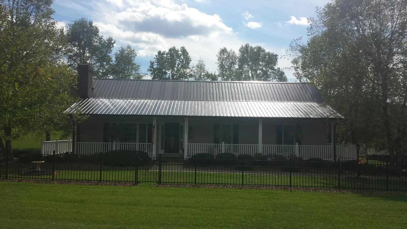 Gray metal roof on a brick ranch with a full width front porch — Gutter Guard Installation work by our crew in Clarkia