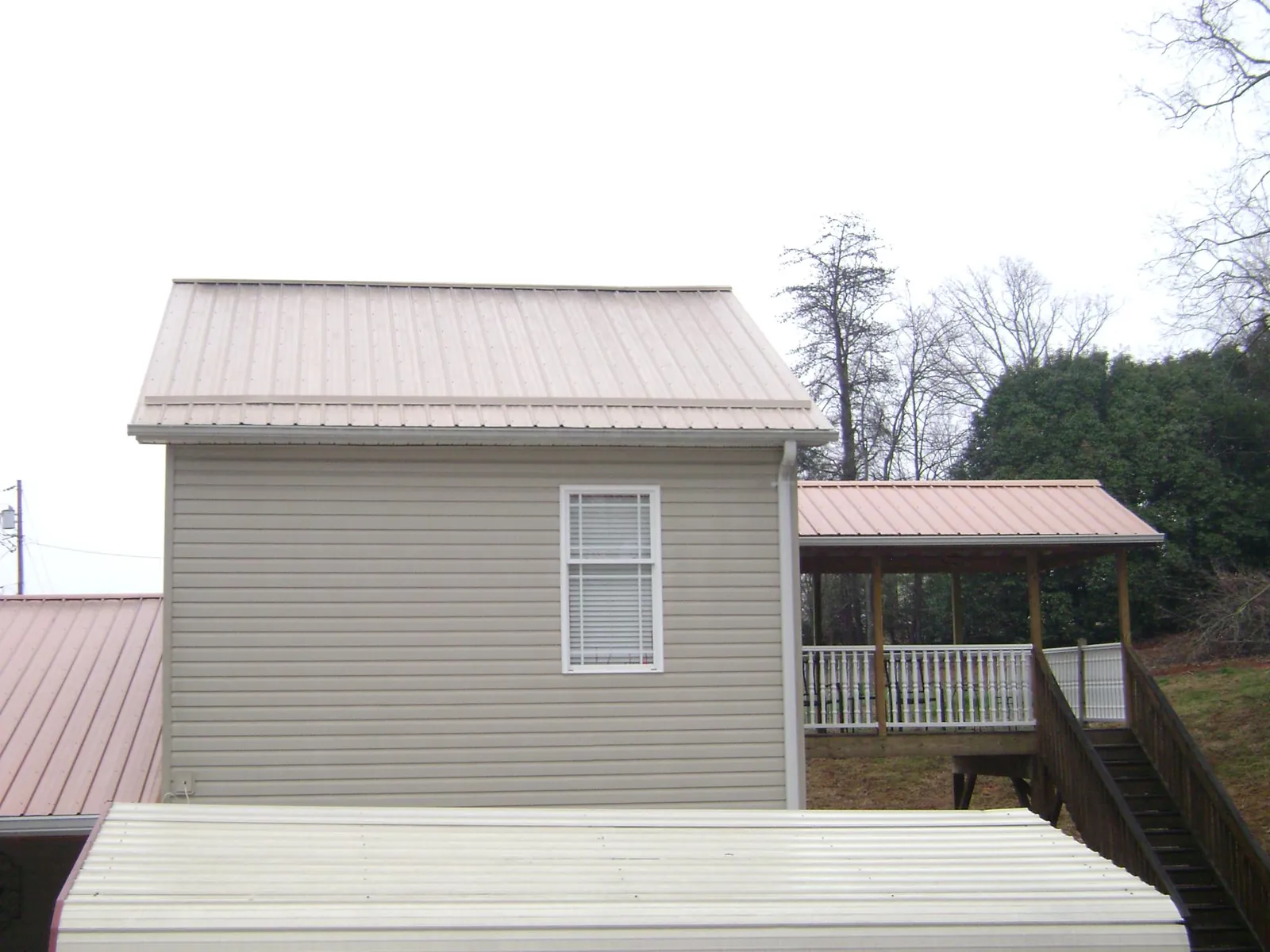 Tan metal roofs on a two story addition and attached porch, from a Roof Replacement job in Clarkia