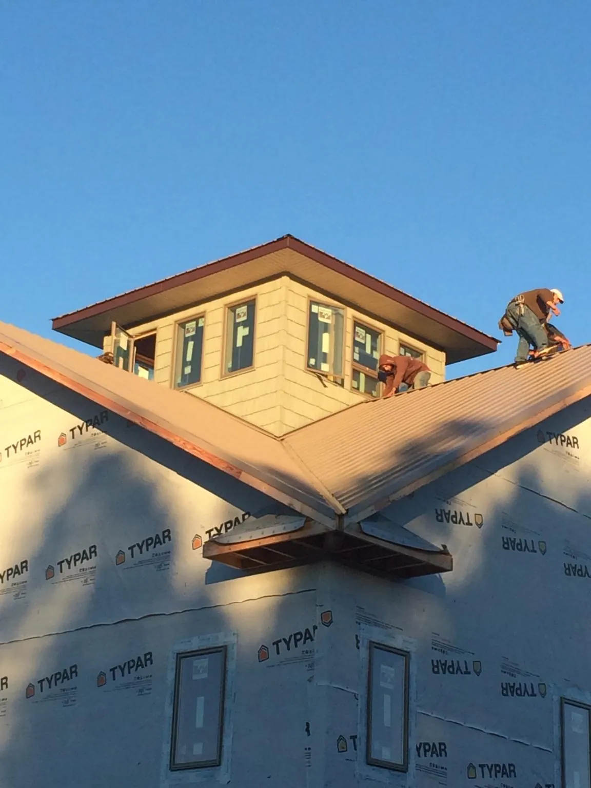 Roofers working around a rooftop cupola on a new metal roof at sunset — Roof Waterproofing in Clarkia by Roofing Brothers